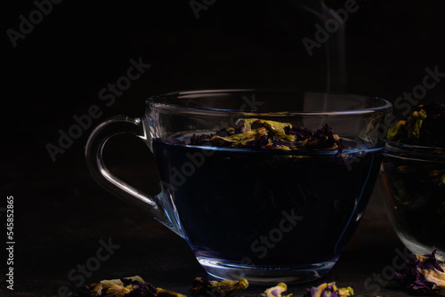 Butterfly pea flower tea in a clear glass on a black background.