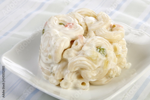 A scoop of macaroni salad with peas and carrots