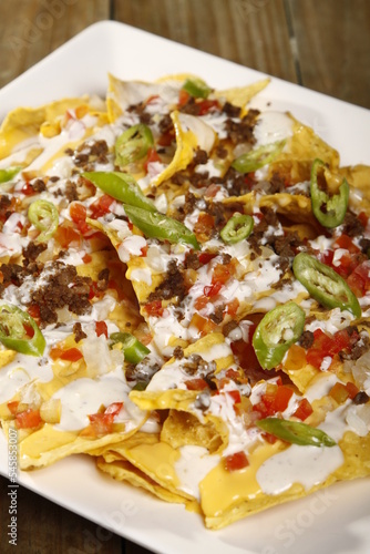 Nachos topped with cheese, garlic sauce, tomatoes and jalapenos