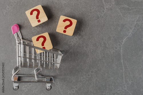 Shopping cart with questions marks on grey background with copy space