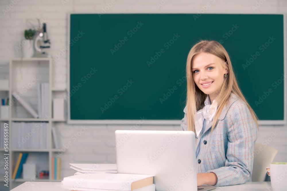 Portrait of smiling young college student studying, sitting at table and writing on notebook in classroom. Portrait of smiling young college student studying, sitting at table and writing on notebook in classroom.