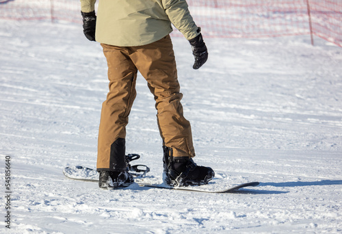 A man zips up a snowboard with boots on the snow.