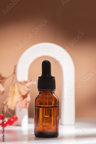 Natural essential oil of viburnum in bottle with a dropper on beige background, with a arch