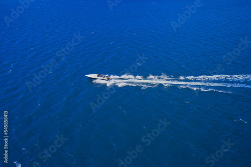 Speed boat in motion. Aerial view of a boat in motion on the water. Top view of the boat in motion. White boat fast movement on blue water.