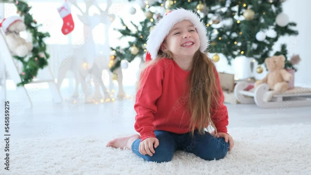 Beautiful child girl smiling emotionally in Christmas time at home. Pretty kid posing in New Year decorated room with festive tree Beautiful child girl smiling emotionally in Christmas time at home. Pretty kid posing in New Year decorated room with festive tree