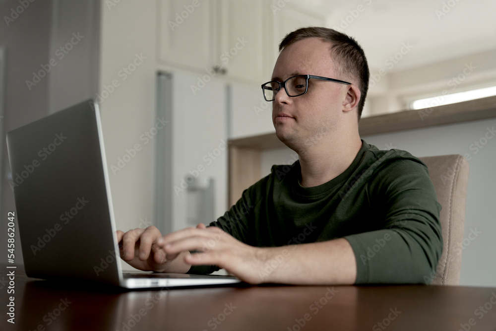 Adult caucasian man with down syndrome using laptop at home Adult caucasian man with down syndrome using laptop at home