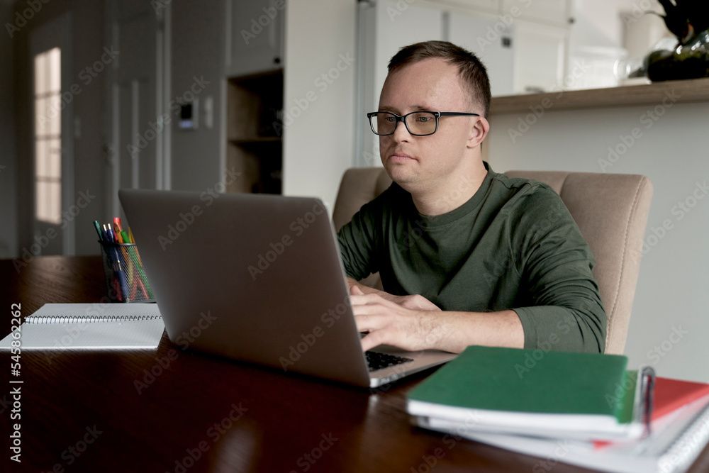 Man with down syndrome using laptop while studying at home Man with down syndrome using laptop while studying at home