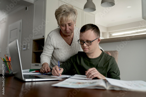 Man with down syndrome learning with his mum at home