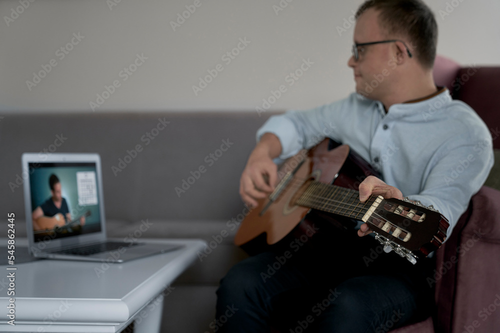 Adult caucasian man with down syndrome learning how to play at guitar Adult caucasian man with down syndrome learning how to play at guitar