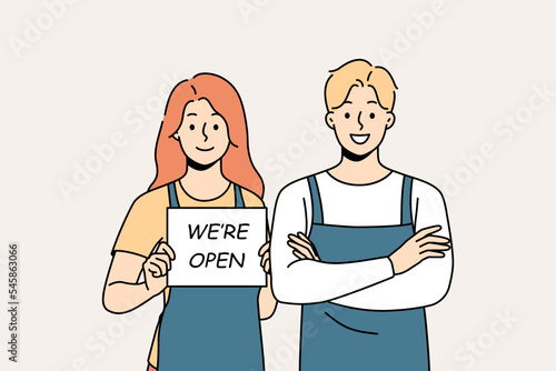 Smiling waiters in aprons hold open sign. Happy man and woman cafe staff notify about shop opening. Vector illustration. 