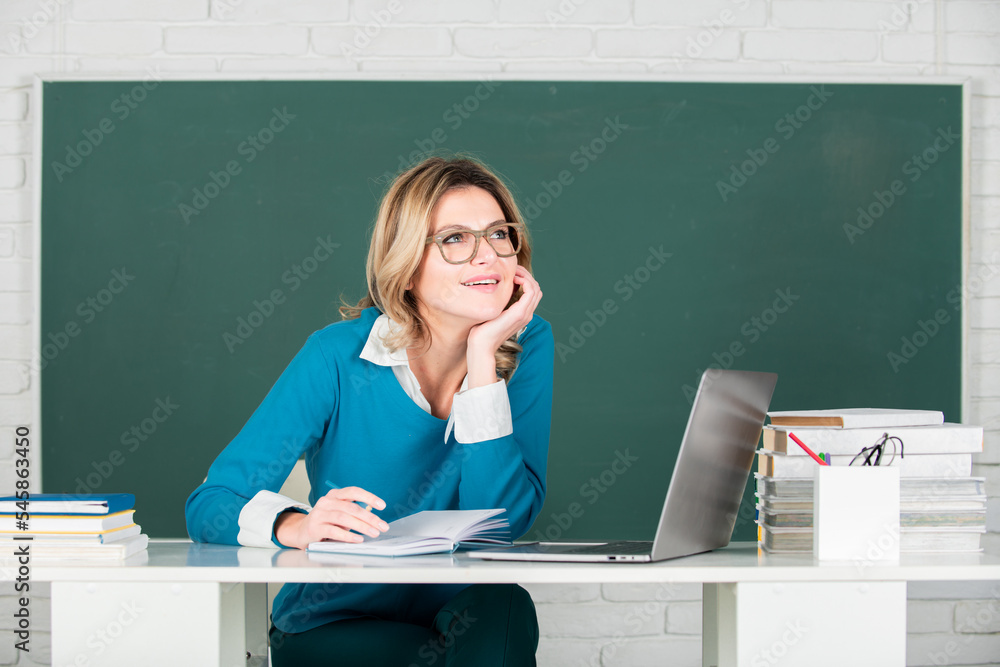 Female teacher. Portrait of female teacher teaching line of high school students with notebook in classroom on blackboard. Female teacher. Portrait of female teacher teaching line of high school students with notebook in classroom on blackboard.