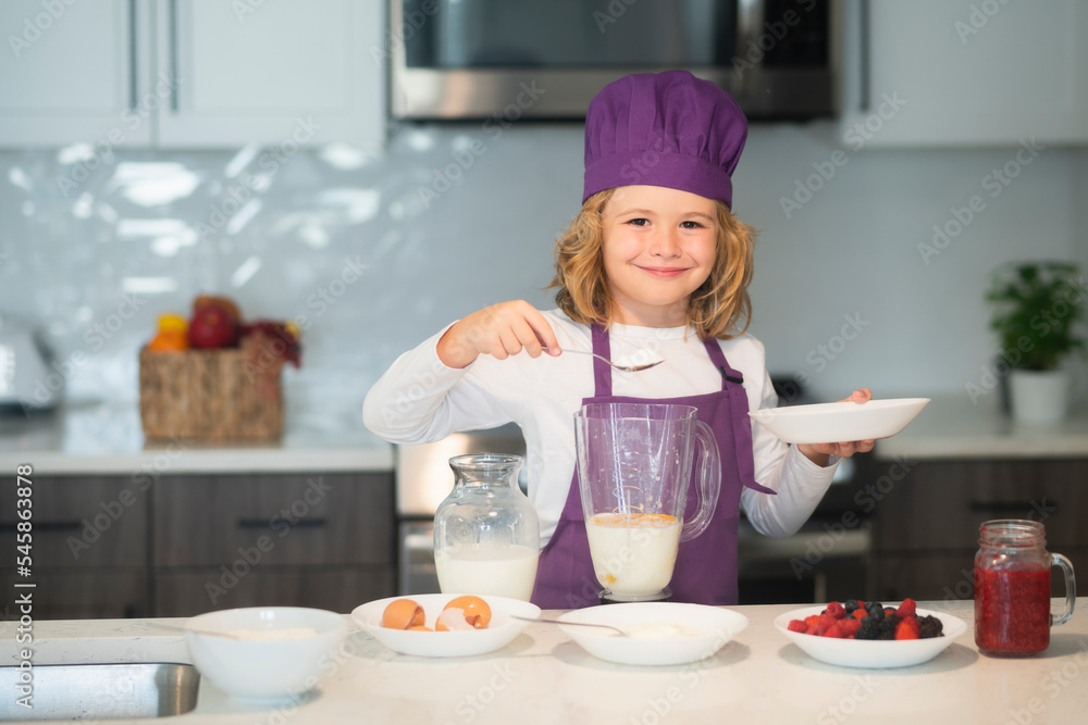 Chef kid preparing tasty food at kitchen. Chef kid boy in apron and chef hat cooking at kitchen. Healthy food. Chef kid preparing tasty food at kitchen. Chef kid boy in apron and chef hat cooking at kitchen. Healthy food.