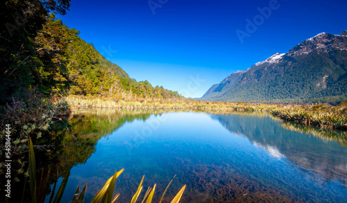 Fototapeta Naklejka Na Ścianę i Meble -  Mirror Lake at Fiordland National Park, Snowy mountains are reflecting in a calm water. New Zealand.
