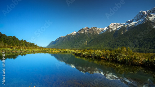 Mirror Lake at Fiordland National Park  Snowy mountains are reflecting in a calm water. New Zealand.