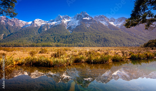 Mirror Lake at Fiordland National Park, Snowy mountains are reflecting in a calm water. New Zealand.
