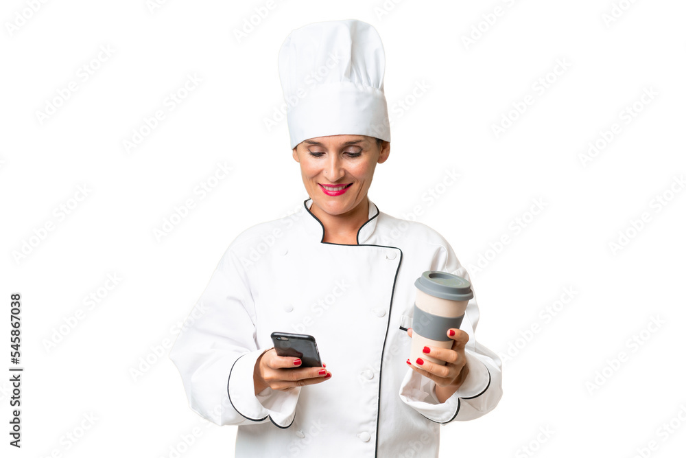 Middle-aged chef woman over isolated background holding coffee to take away and a mobile Middle-aged chef woman over isolated background holding coffee to take away and a mobile