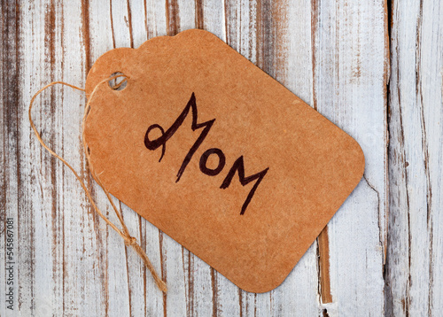 Cardboard gift tag with Mom written on it with rustic wooden surface