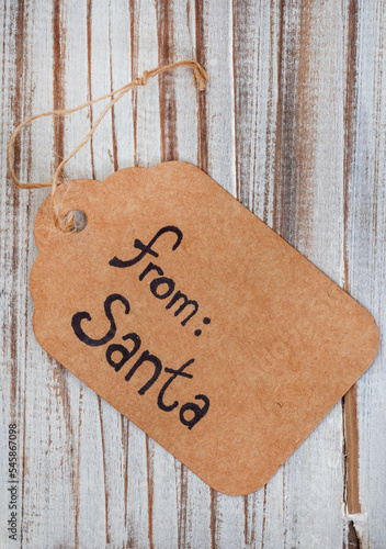 cardboard gift tag with from Santa written on it with a rustic wooden surface