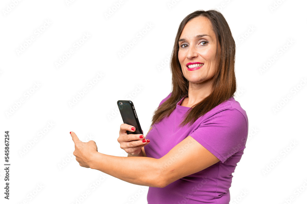 Middle-aged caucasian woman over isolated background using mobile phone and pointing back Middle-aged caucasian woman over isolated background using mobile phone and pointing back