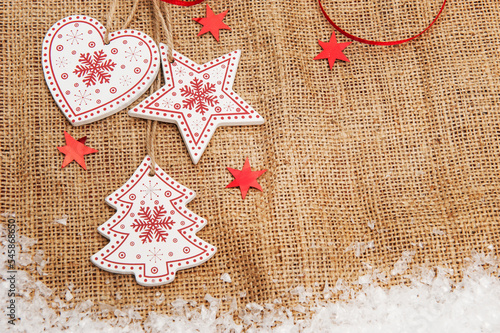Red - white Wooden Christmas decorations on a background of burlap with artificial snow