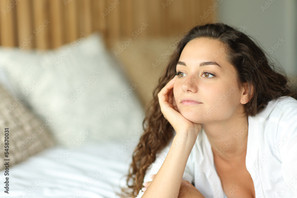 Pensive woman on a bed looking away Pensive woman on a bed looking away