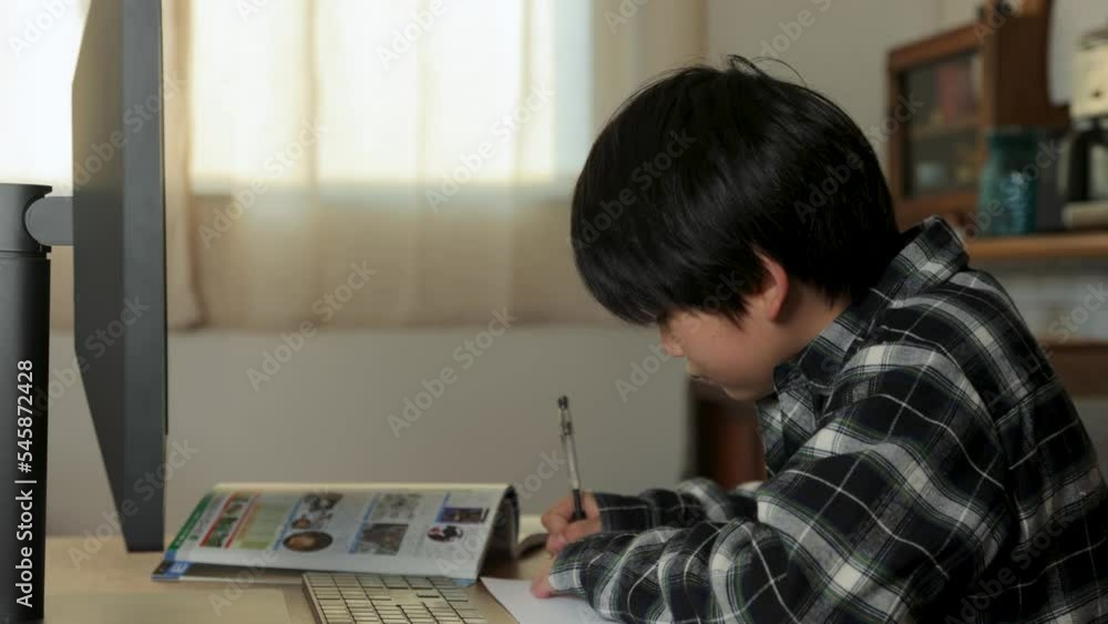 Young Japanese student studying online with big computer monitor. Young Japanese student studying online with big computer monitor.