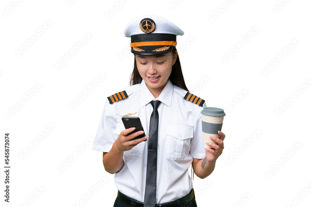 Airplane pilot Asian woman over isolated background holding coffee to take away and a mobile Airplane pilot Asian woman over isolated background holding coffee to take away and a mobile