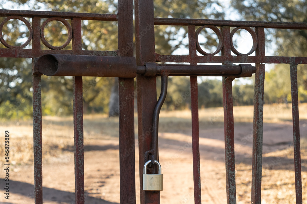 Rustic iron fence closed with a padlock in the countryside Rustic iron fence closed with a padlock in the countryside