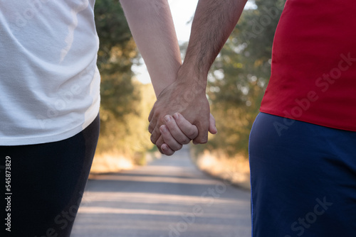 couple of runners hold hands while walking on a mountain road
