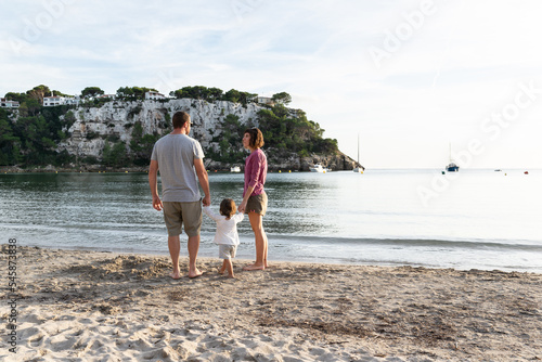 Happy family having a walk in a nice sand beach called cala Galdana located in Minorca, spain. photo