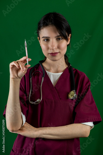  female doctor in a white uniform and gloves with a syringe in her hands poses for the camera