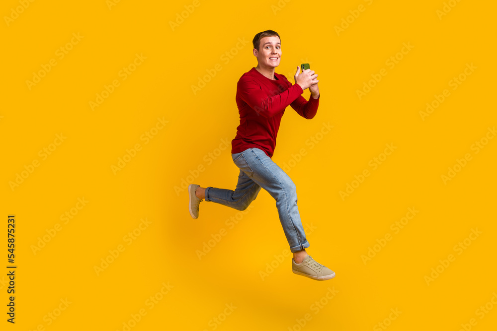 Full body photo of guy jumping high holding telephone rushing wear casual shirt isolated yellow color background