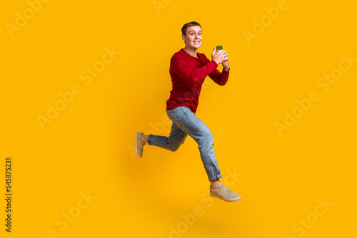 Full body photo of guy jumping high holding telephone rushing wear casual shirt isolated yellow color background