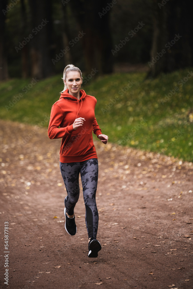 Smiling sportswoman running on footpath Smiling sportswoman running on footpath