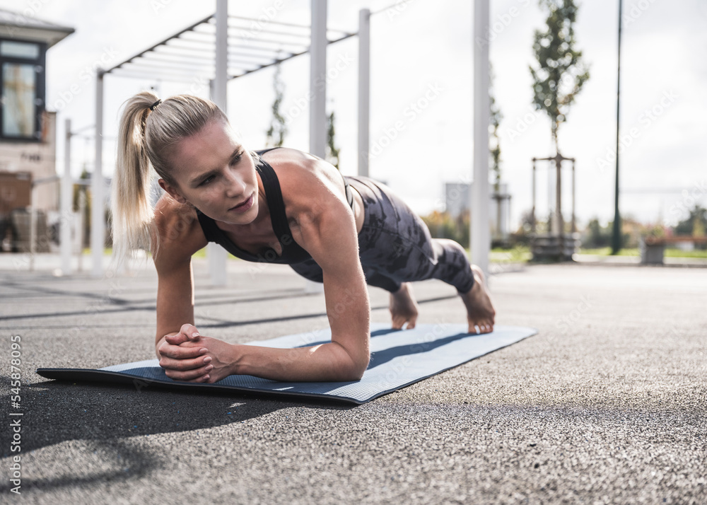 Young sportswoman practicing plank pose on exercise mat Young sportswoman practicing plank pose on exercise mat