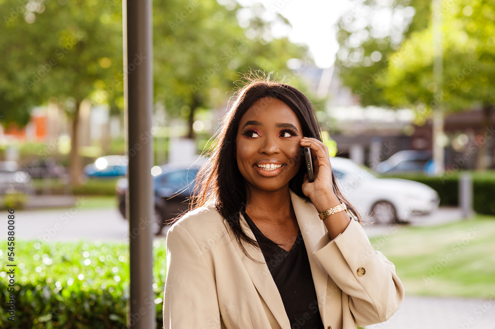 Young black businesswoman talking on cellphone while walking outdoors Young black businesswoman talking on cellphone while walking outdoors