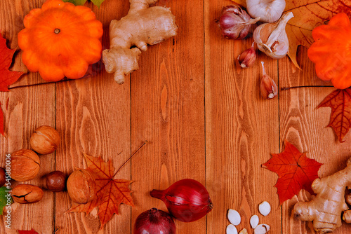 Still life with pumpkin - Pattinson. Red viburnum berry, cranberry.raspberry.Chicory root.Nuts.Red onion. Autumn maple leaves.On a wooden background.meal.the concept of fresh vegetables.place for text
