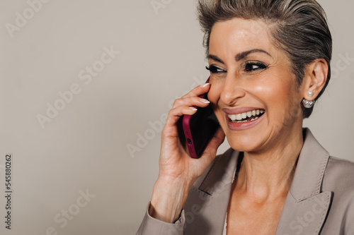 Beautiful senior woman with makeup laughing and talking on cellphone