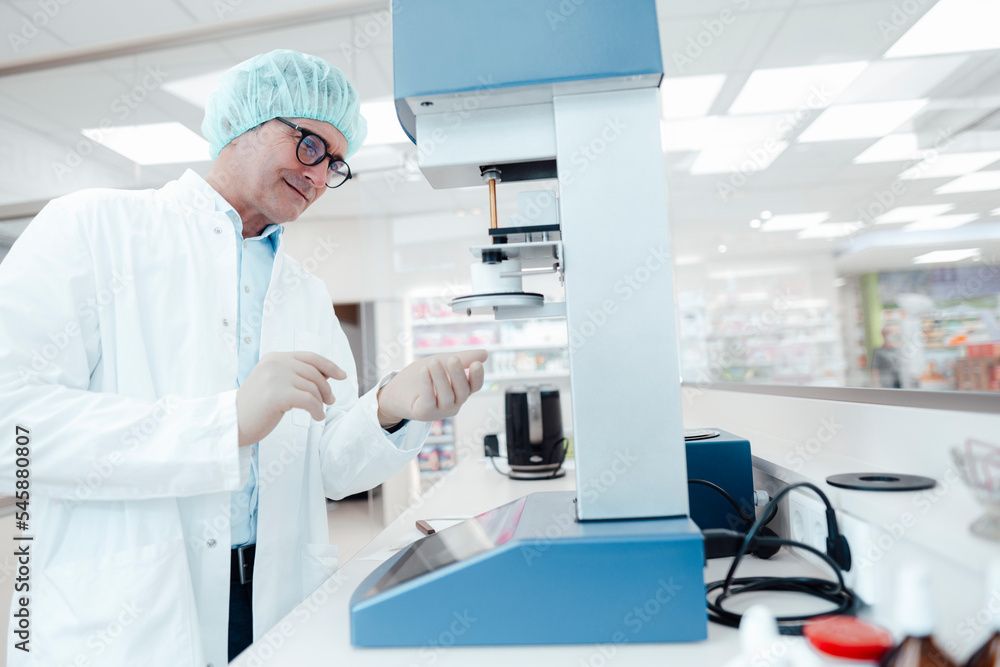 Smiling chemist wearing eyeglasses experimenting in laboratory Smiling chemist wearing eyeglasses experimenting in laboratory