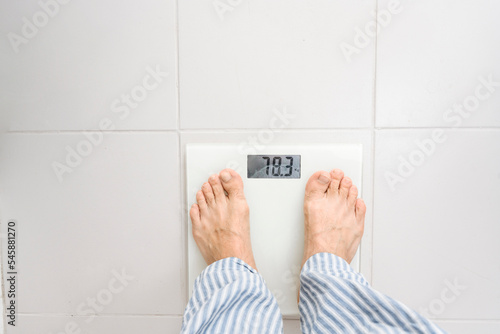 Man standing on weight scale at home photo