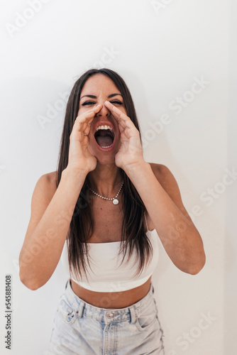 Woman with long hair shouting in front of white wall