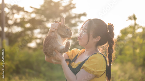 Woman holding cute fluffy Bunny on park outdoors. Friendship with Easter Bunny.