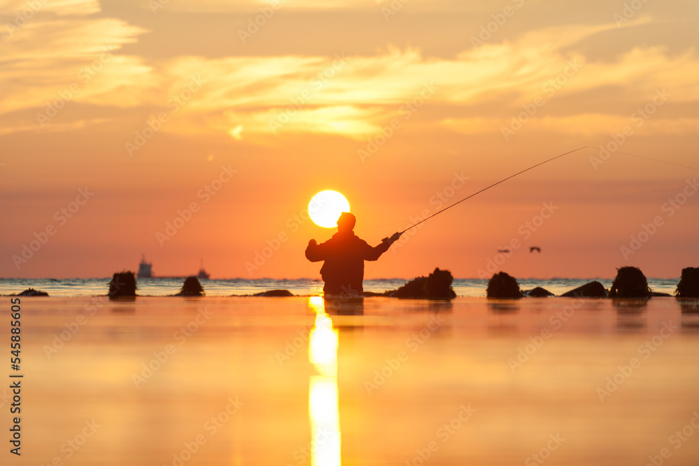 Rear view of man fishing in sea at sunset Rear view of man fishing in sea at sunset