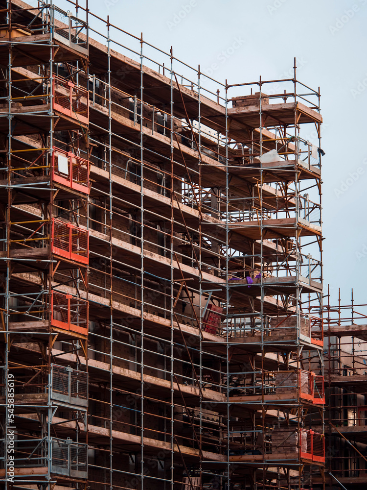 Construction site with modern building in scaffolding. Brick house, residential or commercial property development.