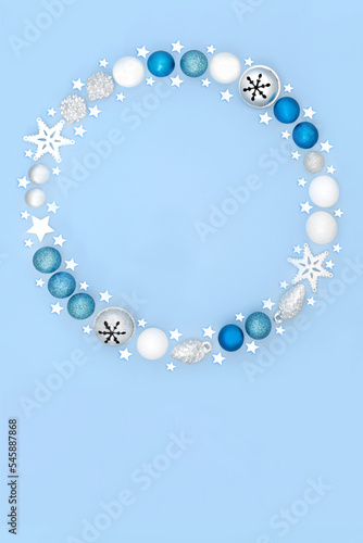 Magical Christmas wreath with tree bauble decorations on pastel blue background. Festive fantasy abstract concept for winter Xmas and New Year.
