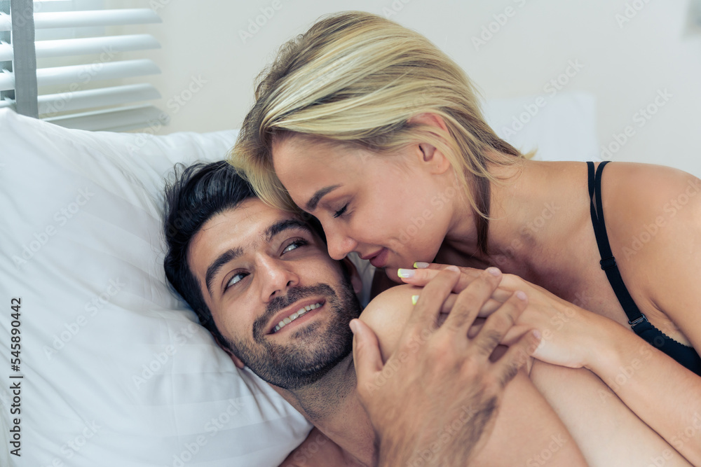 Fototapeta premium Caucasian young man and woman starting foreplay and making love on bed. 
