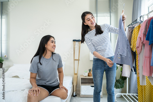 Asian young amputee leg woman and friend choosing clothes on closet rack. photo