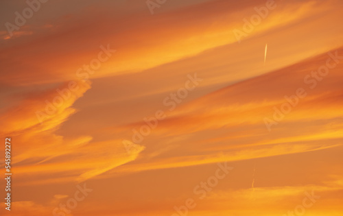 Amazing orange sunset sky. Beautiful sky and clouds color with airplane tracks.
