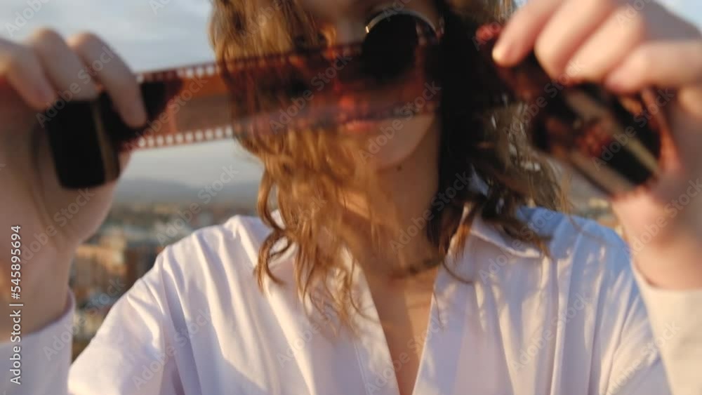 Attractive curly hair female with sunglasses looking photo film roll in the city Attractive curly hair female with sunglasses looking photo film roll in the city