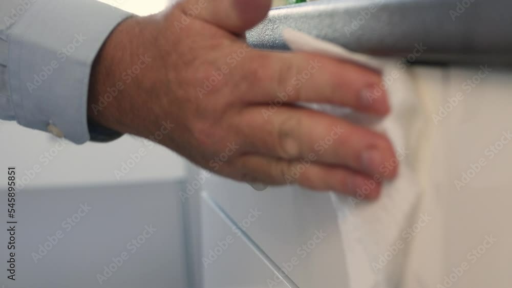 Blurred Shooting with a Man Cleaning and Sanitizing the Kitchen Furniture. Disinfecting the Surface of a Drawer with a Wipe and Cleaning Detergent. Blurred Shooting with a Man Cleaning and Sanitizing the Kitchen Furniture. Disinfecting the Surface of a Drawer with a Wipe and Cleaning Detergent.